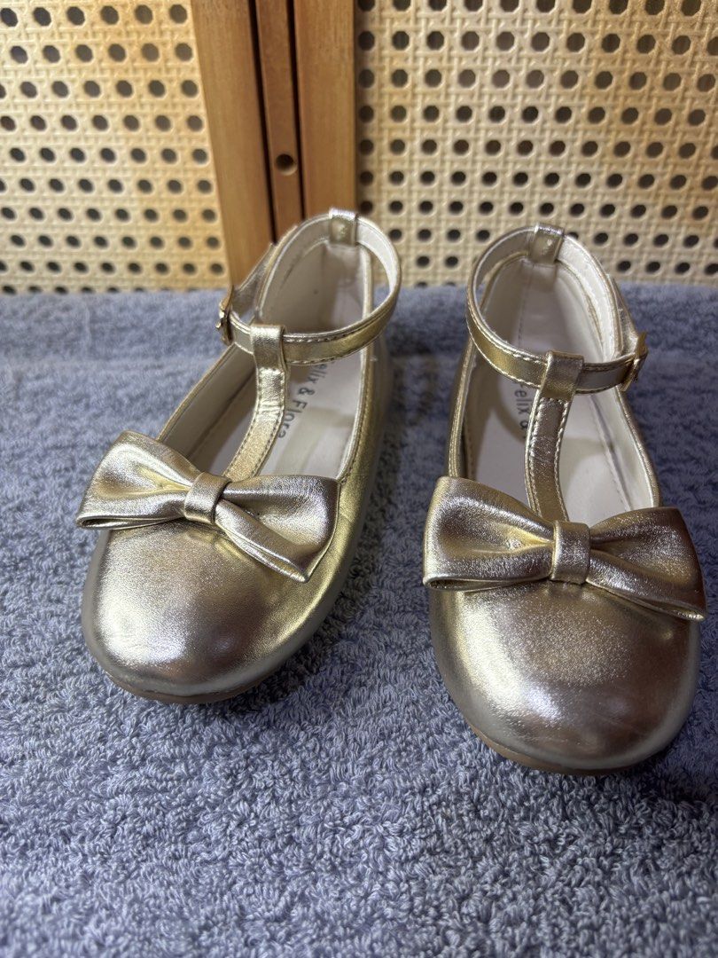 Felix & Flora Gold T-Bar Flats with Bow (Category: Babies & Kids Fashion) located in Manila. Submitted by wardrobeinmnl (Listing ID 1467892049, Image 2). Description: Size: 10 - Brand: Felix & Flora - Color/Finish: Gold metallic - Design: T-bar strap with buckle closure and cute toe bow - Condition: Clean insoles and neat stitching - Versatile: Great for parties, weddings, or everyday wear.
