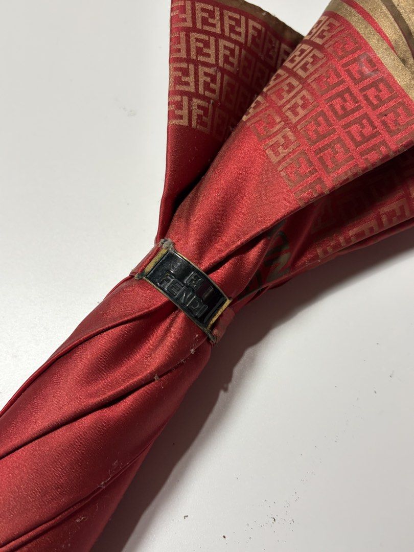 Fendi Monogram Umbrella (Category: Umbrellas) located in Manila. Submitted by swaaaaggy (Listing ID 1467860452, Image 2). Description: - Authentic Fendi monogram umbrella - Striking red fabric with gold FF logo border and details - Elegant curved wooden handle with engraved Fendi hardware - Branded snap button strap closure - Pre-loved condition (approx. 7/10) with minor signs of wear - Stylish designer accessory for rain or sun protection.