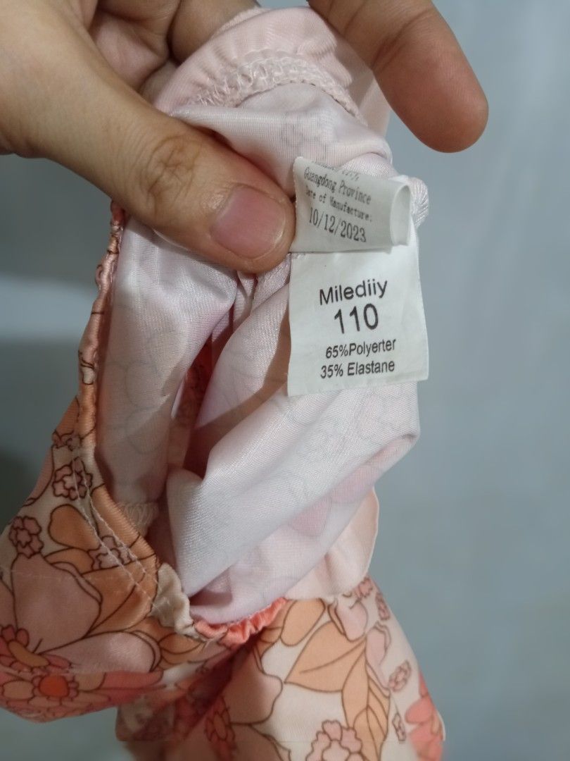 Floral Long Sleeve Swimsuit Size 110 (Category: Babies & Kids Fashion) located in Bacoor. Submitted by thriftworksph (Listing ID 1467938021, Image 3). Description: - Brand: Miledii - Item: Kids long sleeve swimsuit - Design: Cream base with all-over orange and peach floral pattern - Features: Half-zip front with white zipper, adorable ruffle detail around leg openings - Size: 110 (Tag) - Material: 65% polyester, 35% elastane - Manufacture Date: O