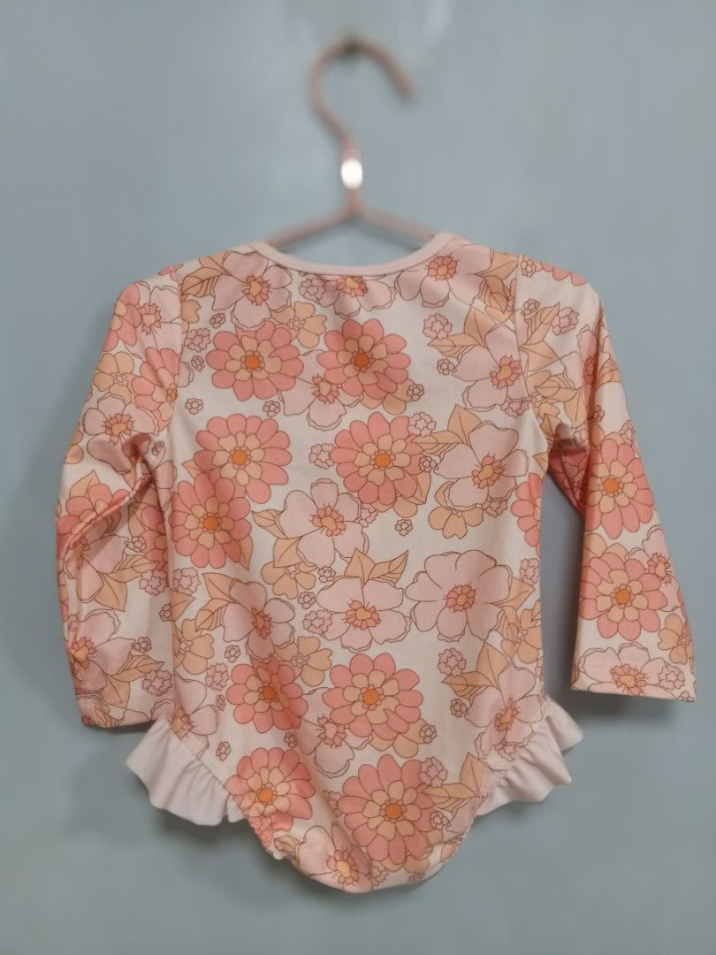 Floral Long Sleeve Swimsuit Size 110 (Category: Babies & Kids Fashion) located in Bacoor. Submitted by thriftworksph (Listing ID 1467938021, Image 2). Description: - Brand: Miledii - Item: Kids long sleeve swimsuit - Design: Cream base with all-over orange and peach floral pattern - Features: Half-zip front with white zipper, adorable ruffle detail around leg openings - Size: 110 (Tag) - Material: 65% polyester, 35% elastane - Manufacture Date: O