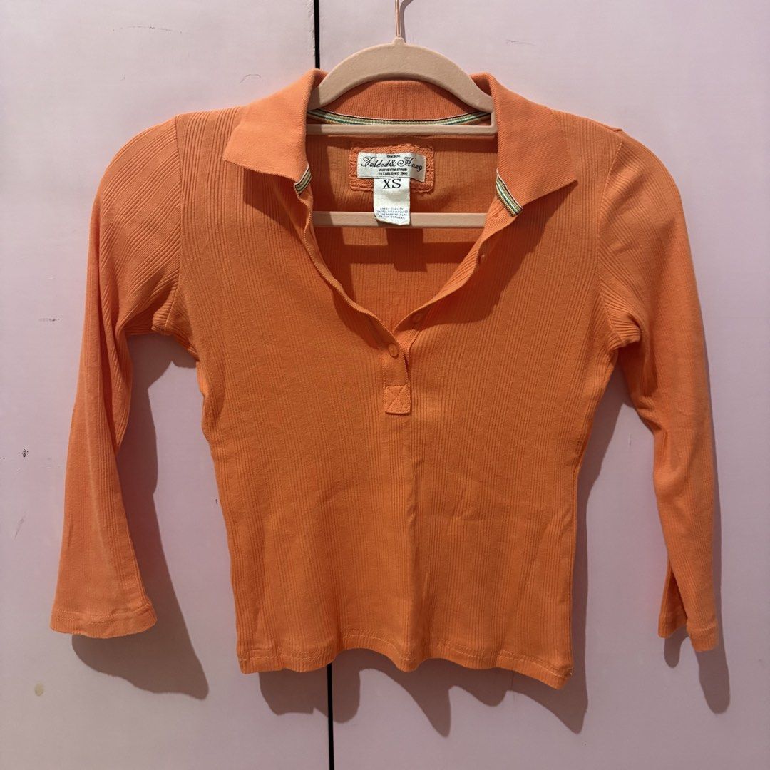 Folded & Hung Orange Ribbed Polo Top Size XS (Category: Shirts) located in Taguig. Submitted by xoalexv (Listing ID 1468010363, Image 1). Description: - Brand: Folded & Hung - Size: XS - Color: Bright orange - Material: Soft, stretchy ribbed knit fabric - Design: Collared neckline, button placket, 3/4 sleeves - Fit: Fitted cut - Perfect for layering or everyday casual wear.