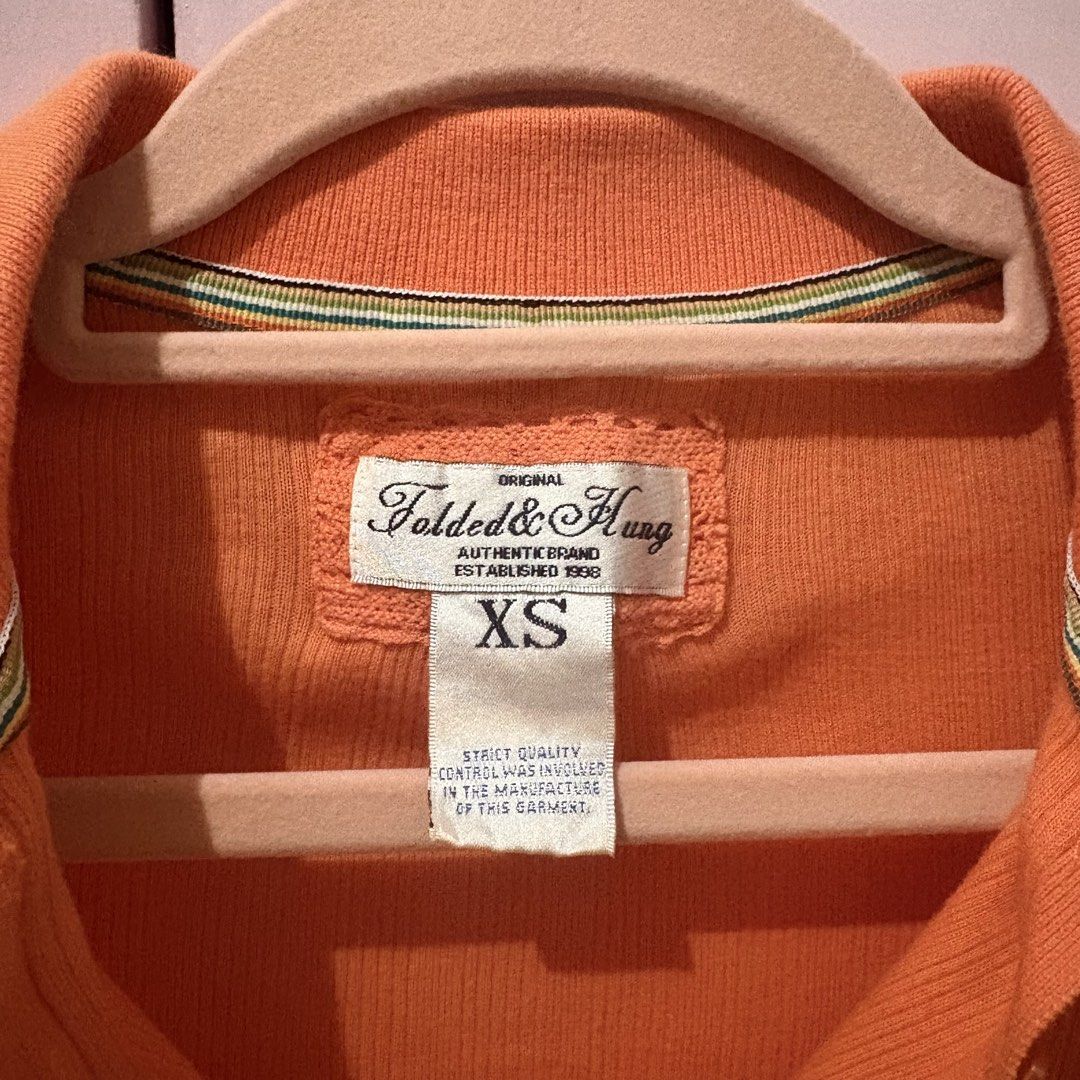 Folded & Hung Orange Ribbed Polo Top Size XS (Category: Shirts) located in Taguig. Submitted by xoalexv (Listing ID 1468010363, Image 2). Description: - Brand: Folded & Hung - Size: XS - Color: Bright orange - Material: Soft, stretchy ribbed knit fabric - Design: Collared neckline, button placket, 3/4 sleeves - Fit: Fitted cut - Perfect for layering or everyday casual wear.
