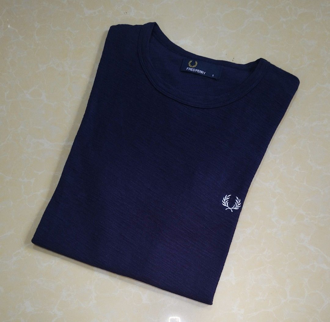Fred Perry Navy Blue T-Shirt Size S (Category: Tshirts & Polo Shirts ) located in Manila. Submitted by purefire-477a (Listing ID 1467851115, Image 3). Description: - Brand: Fred Perry - Color: Navy Blue - Size: Small - Logo: Iconic white embroidered laurel wreath on chest - Fit: Standard fit with short sleeves - Material: Soft and textured fabric - Condition: Clean, zero flaws found.