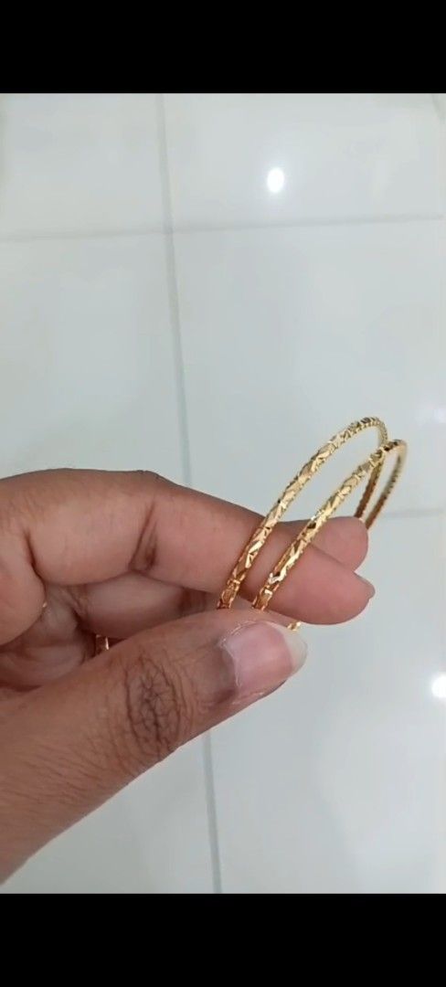 Gold patterned bangles set (Category: Bracelets) located in Singapore. Submitted by maria7971 (Listing ID 1468047813, Image 1). Description: Two slim, gold-tone bangles featuring a textured geometric pattern and a shiny finish. Lightweight and versatile for daily wear or stacking. Grab them now to elevate your everyday look! Weight:17.18g solid bangle 2.6cm.