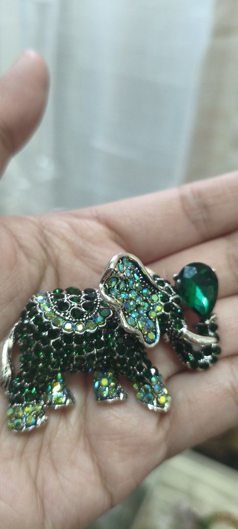 Green Crystal Elephant Brooch Pin (Category: Brooches) located in Quezon City. Submitted by gemaicloset (Listing ID 1467941274, Image 1). Description: - Design: Eye-catching green crystal elephant brooch with silver-tone metal backing - Details: Covered in sparkling green rhinestones with a large teardrop crystal held in the trunk - Features: Secure pin closure and Chinese characters stamped on the back - Size: Measures a few inches across - Vers