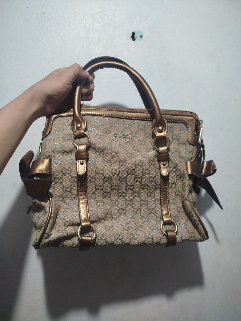 Gucci GG Monogram Metallic Gold Handbag (Category: Luxury Bags & Wallets) located in Manila. Submitted by alenoid (Listing ID 1467951825, Image 1). Description: - Gucci shoulder bag in classic GG monogram canvas - Elegant metallic gold leather handles and trim with chic side ribbon accents - Secure zip top closure - Roomy interior featuring a zippered pocket and official Gucci 'Made in Italy' hardware plate - Ideal everyday luxury bag for work or
