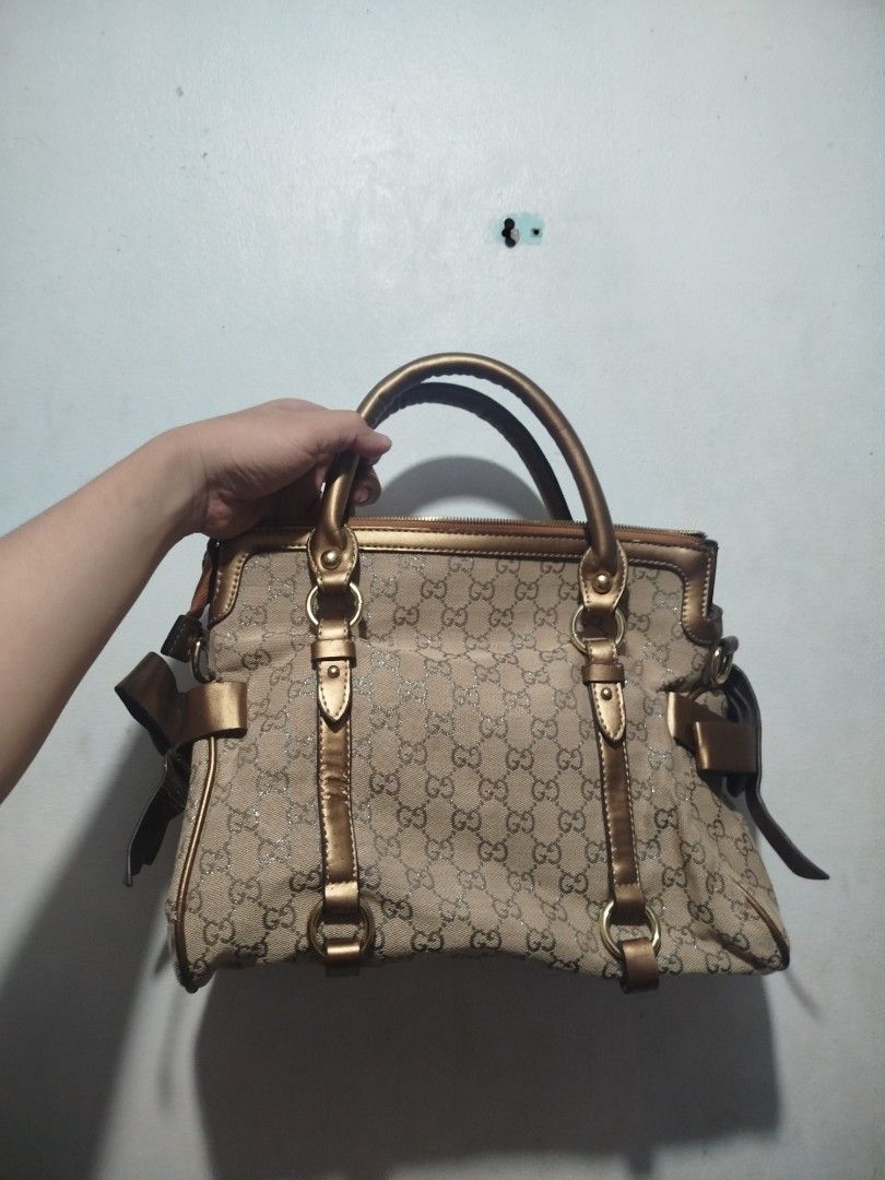Gucci GG Monogram Metallic Gold Handbag (Category: Luxury Bags & Wallets) located in Manila. Submitted by alenoid (Listing ID 1467951825, Image 2). Description: - Gucci shoulder bag in classic GG monogram canvas - Elegant metallic gold leather handles and trim with chic side ribbon accents - Secure zip top closure - Roomy interior featuring a zippered pocket and official Gucci 'Made in Italy' hardware plate - Ideal everyday luxury bag for work or