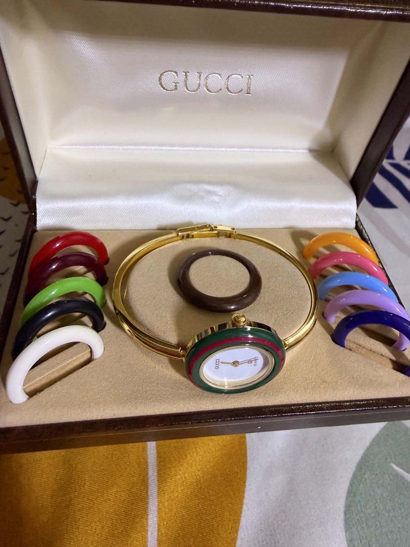 Gucci Interchangeable Bezel Bangle Watch with Original Box (Category: Women's Watches) located in Pasig City. Submitted by melaiski28 (Listing ID 1467852849, Image 2). Description: - Authentic vintage Gucci bangle watch - Classic gold-tone finish with a clean white dial - Includes 8 interchangeable colorful bezels (red, green, black, white, orange, pink, blue, purple) - Comes with original fitted, velvet-lined presentation box - Excellent collect