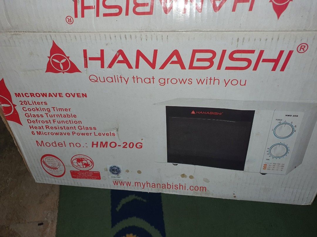 Hanabishi MICROWAVE Oven HMO-20G 20L (Category: Ovens & Toasters) located in Quezon City. Submitted by carbonfootprint (Listing ID 1467946804, Image 1). Description: ✔️Hanabishi microwave oven model ✔️HMO-20G with twenty-liter capacity. ✔️Includes original box, rotating glass plate, and interior roller ring. ✔️Dual rotary dials control power levels and cooking timer. ✔️White exterior housing with black front door panel and red branding. NEVER USE