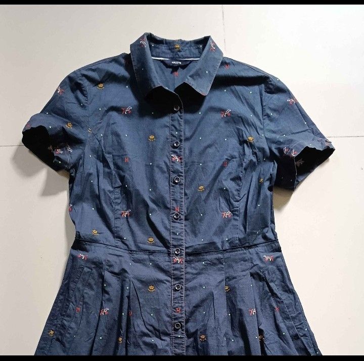 Hazzys Navy Blue Button Down Dress (Category: Dresses) located in Cebu City. Submitted by mcmapio (Listing ID 1467966782, Image 1). Description: - Brand: Hazzys - Color: Navy blue with cute embroidered crowns, dogs, and red H logos - Style: Short-sleeve shirt dress, button-down front, collared neckline, and pleated skirt - Size: 165/88A - Material: Lightweight, breathable cotton - Versatile: Great for daily wear, office outfits, or weekend lakad 