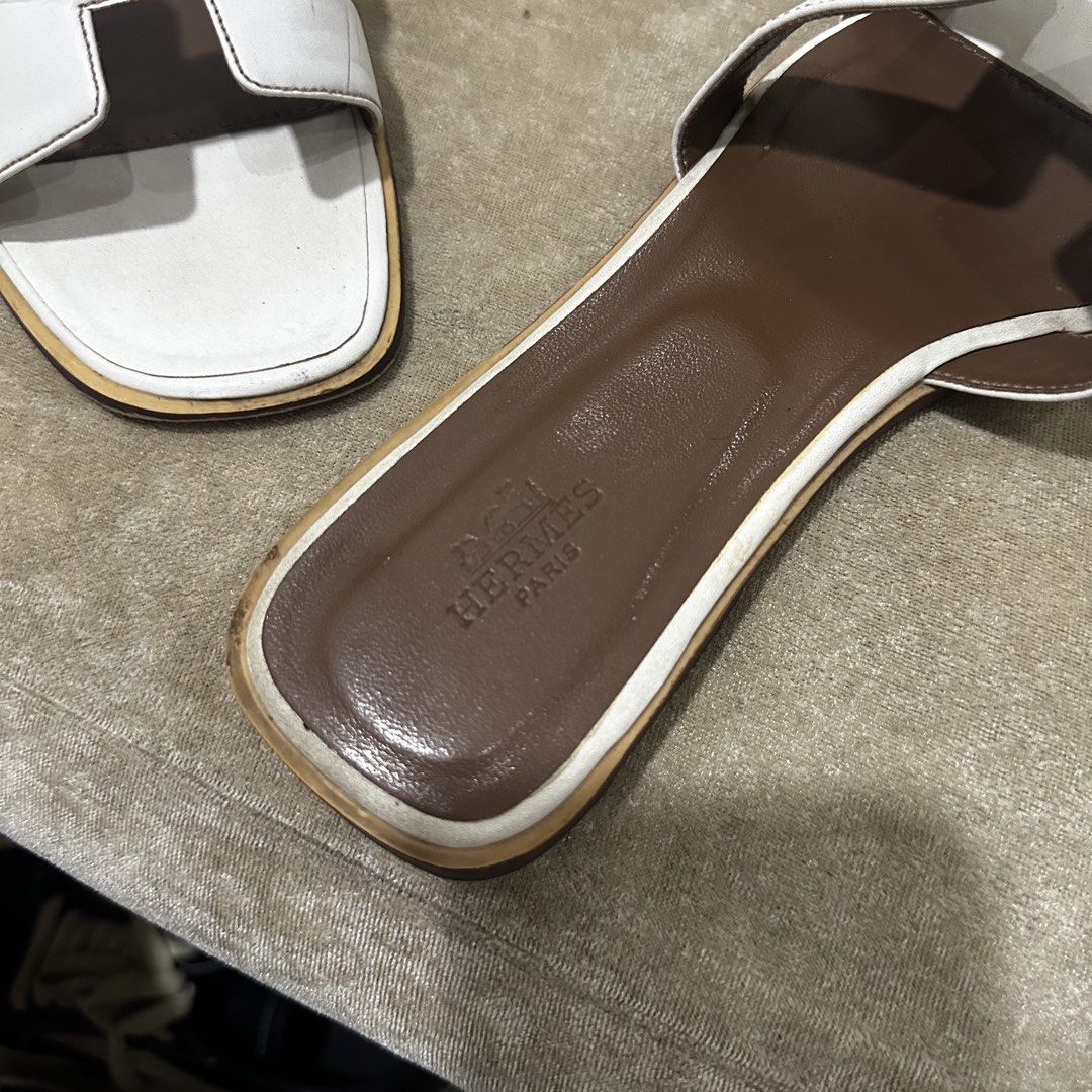 Hermes Oran White Leather Sandals Size 38 (Category: Flats & Sandals) located in Quezon City. Submitted by retroboominwantsummoh (Listing ID 1467966162, Image 2). Description: - Brand: Hermes - Style: Iconic H strap sandals - Color: White leather with brown insoles - Size: 38 (Made in Italy) - Condition: Leather uppers are clean with minimal creasing; soles show visible dirt and scuffing from previous wear - Perfect for adding effortless luxury t