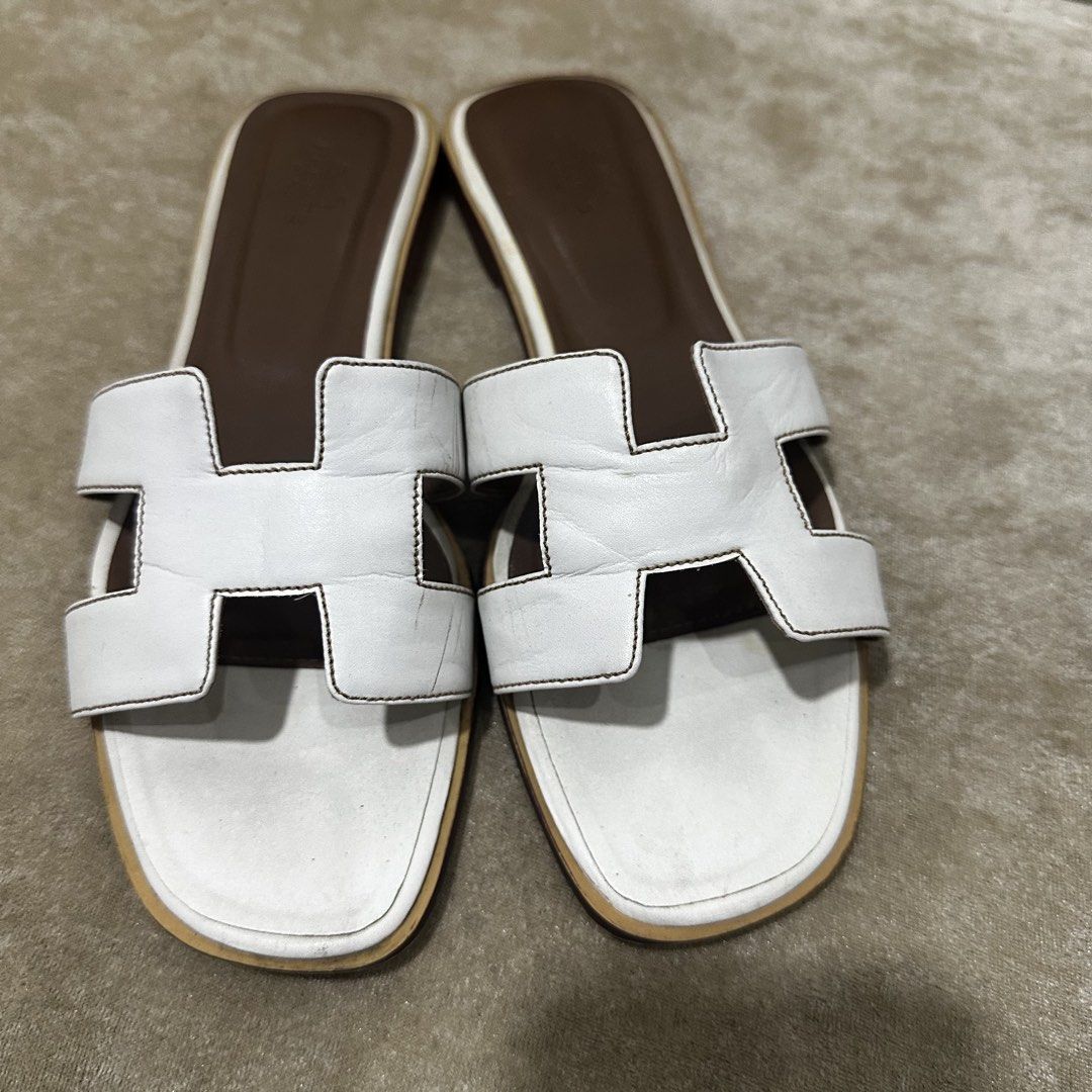 Hermes Oran White Leather Sandals Size 38 (Category: Flats & Sandals) located in Quezon City. Submitted by retroboominwantsummoh (Listing ID 1467966162, Image 3). Description: - Brand: Hermes - Style: Iconic H strap sandals - Color: White leather with brown insoles - Size: 38 (Made in Italy) - Condition: Leather uppers are clean with minimal creasing; soles show visible dirt and scuffing from previous wear - Perfect for adding effortless luxury t