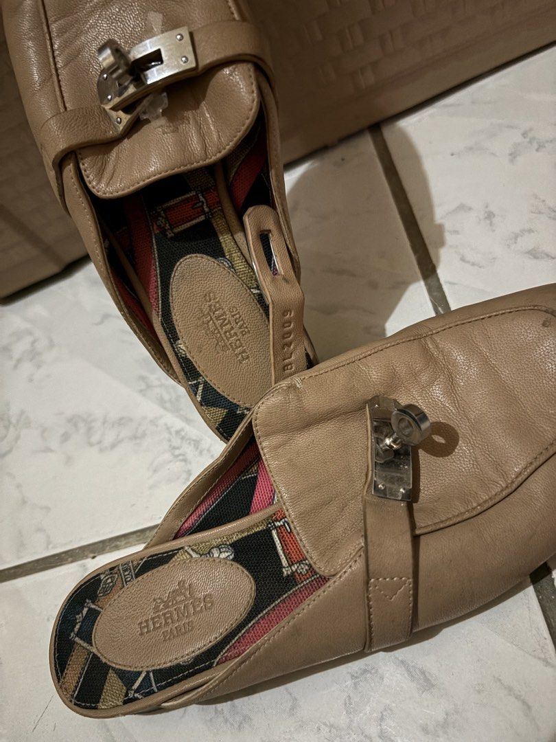 Hermès Kelly Buckle Leather Mules (Category: Sneakers & Footwear) located in Manila. Submitted by bellepatal57826 (Listing ID 1467865423, Image 2). Description: - Brand: Hermès - Style: Slip-on leather mules - Color: Classic tan - Hardware: Iconic silver-tone Kelly lock - Lining: Colorful patterned fabric - Insole: Tan leather with embossed Hermès Paris stamp - Condition: Pre-loved, showing visible creasing on the upper leather and normal wear on