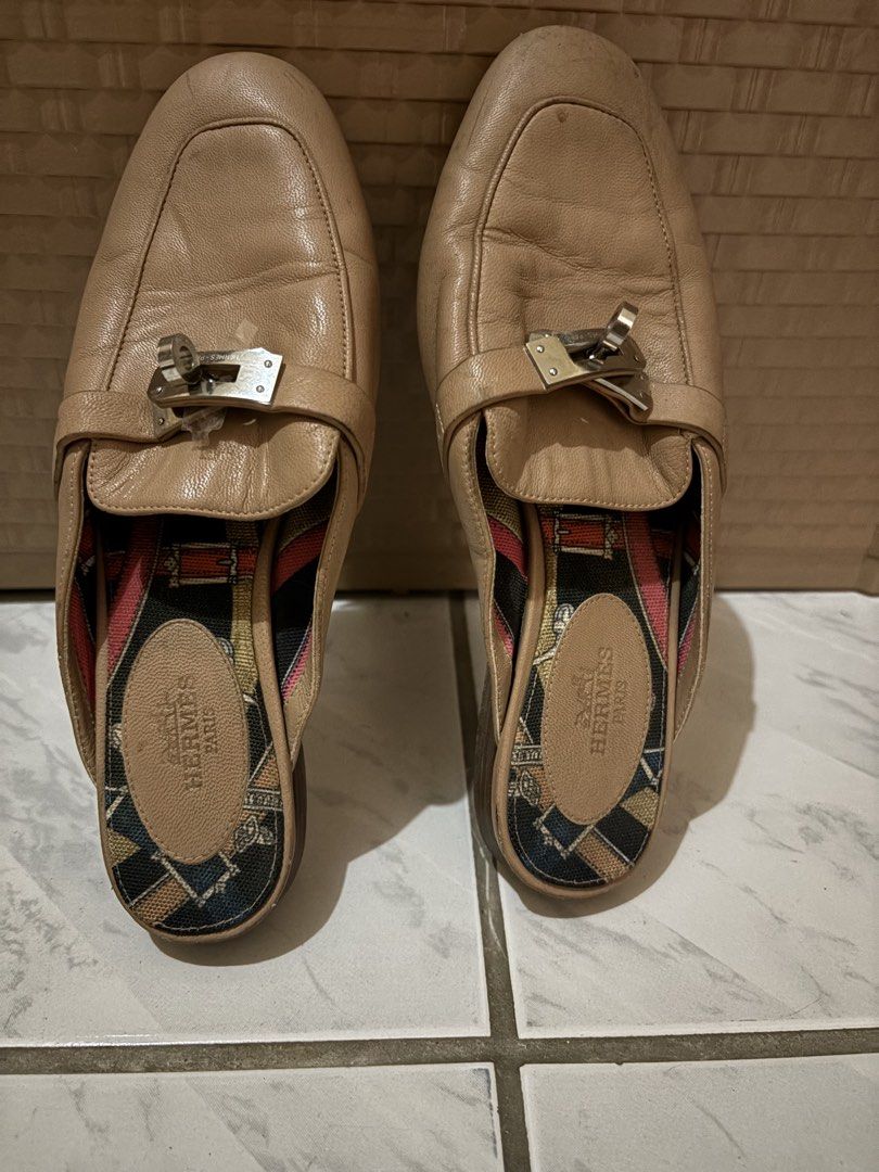 Hermès Kelly Buckle Leather Mules (Category: Sneakers & Footwear) located in Manila. Submitted by bellepatal57826 (Listing ID 1467865423, Image 1). Description: - Brand: Hermès - Style: Slip-on leather mules - Color: Classic tan - Hardware: Iconic silver-tone Kelly lock - Lining: Colorful patterned fabric - Insole: Tan leather with embossed Hermès Paris stamp - Condition: Pre-loved, showing visible creasing on the upper leather and normal wear on