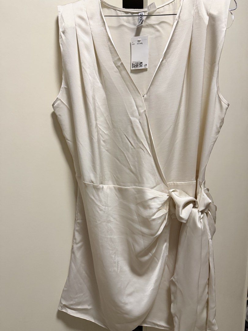 H&M Divided White Wrap Dress with Side Bow (Category: Dresses) located in Candelaria. Submitted by thv_bibi (Listing ID 1468009550, Image 1). Description: - Brand: H&M Divided - Style: Sleeveless white wrap dress with V-neck and pleated shoulder details - Material: Silky satin-like finish - Extras: Includes a matching side tie belt with a bow detail - Condition: Brand new with original store tag attached - Sizing: EUR sizing Original price: 1490 