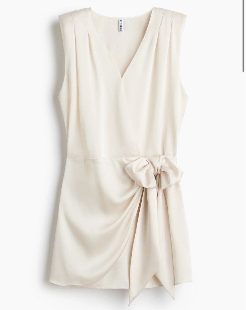 H&M Divided White Wrap Dress with Side Bow (Category: Dresses) located in Candelaria. Submitted by thv_bibi (Listing ID 1468009550, Image 3). Description: - Brand: H&M Divided - Style: Sleeveless white wrap dress with V-neck and pleated shoulder details - Material: Silky satin-like finish - Extras: Includes a matching side tie belt with a bow detail - Condition: Brand new with original store tag attached - Sizing: EUR sizing Original price: 1490 