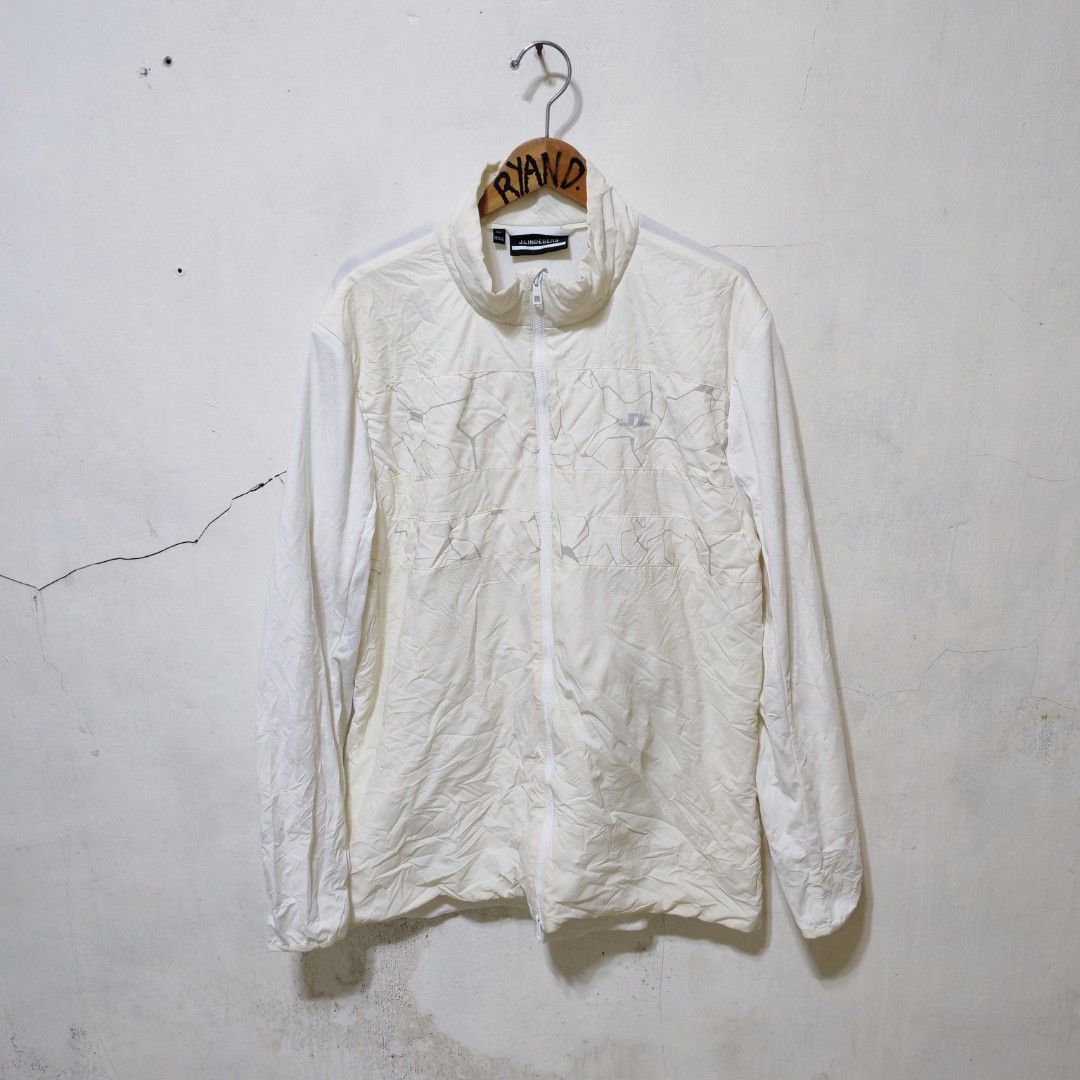 j.lindeberg White Windbreaker Jacket (Category: Coats, Jackets and Outerwear) located in Manila. Submitted by ryandip88861707 (Listing ID 1467859548, Image 1). Description: - Brand: J.Lindeberg - Color: Off-white - Size: XXL (Made in Vietnam) - Design: Full-zip with stand collar and geometric chest panel featuring the bridge logo - Packable: Packs into its own integrated pouch with a carrying loop - Flaw: Small yellow stain near the bottom front.