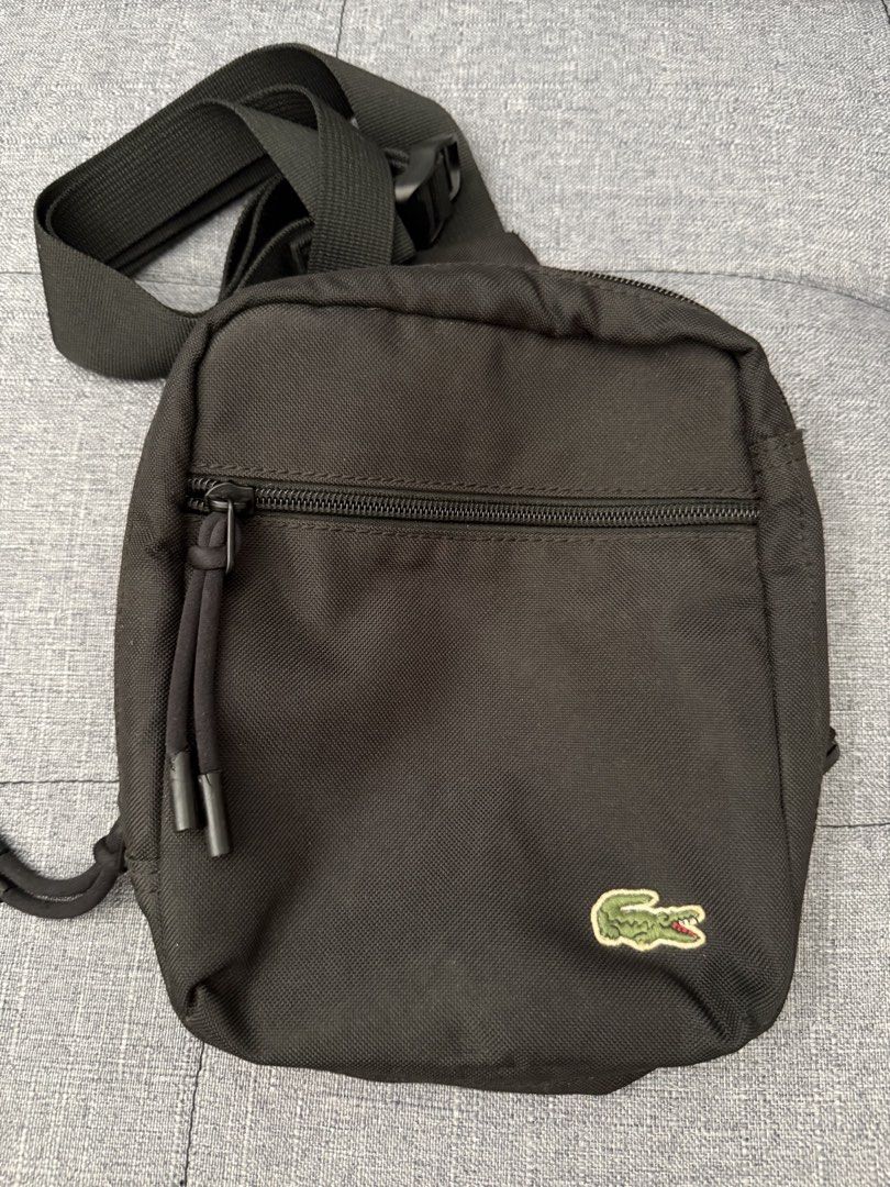 Lacoste Black Crossbody Sling Bag (Category: Sling Bags) located in Pasay City. Submitted by el.sole (Listing ID 1467530605, Image 2). Description: 👉FREE SHIPPING!!! (Within MetroManila Only) 👉FREE SHIPPING!!! (Luzon,Visayas and Mindanao) via J&T or LBC 👉Repriced: May natanggal na bilog (please see photo in red circle and arrow). See photo. But in good condition in the bag. - Brand: Lacoste - Color: Classic Black - Design: Compact crossbody ba