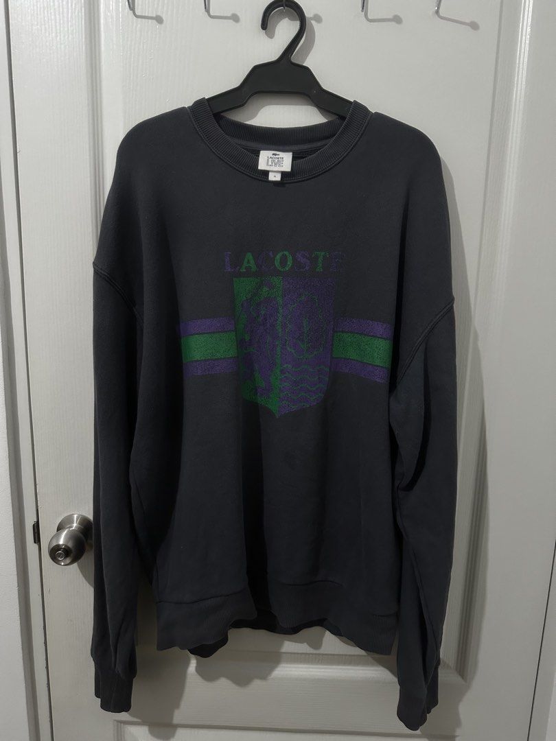 Lacoste Live Crest Logo Dark Grey Sweatshirt Size M (Category: Coats, Jackets and Outerwear) located in Manila. Submitted by driftthrift (Listing ID 1467894392, Image 1). Description: - Brand: Lacoste Live - Style: Crewneck sweatshirt - Color: Dark grey - Size: M (fit large to xl) - Material: 100% cotton - Design: Large green and purple chest graphic with stripes, iconic embroidered crocodile logo on the back collar - Details: Ribbed cuffs, hem, 