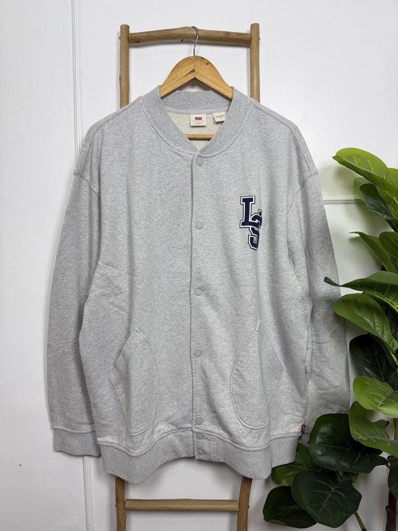 Levi's Bomber Cardigan (Category: Coats, Jackets and Outerwear) located in Silang. Submitted by estilocavph (Listing ID 1467942092, Image 2). Description: - Brand: Levi's - Item: Bomber Cardigan - Color: Grey with contrast navy blue LS varsity patch - Size: Large (Relaxed fit) - Closure: Snap button front - Pockets: Dual front pockets - Details: Ribbed cuffs, collar, and hem - Condition: Brand new with original paper tag attached Dimensions: L30.