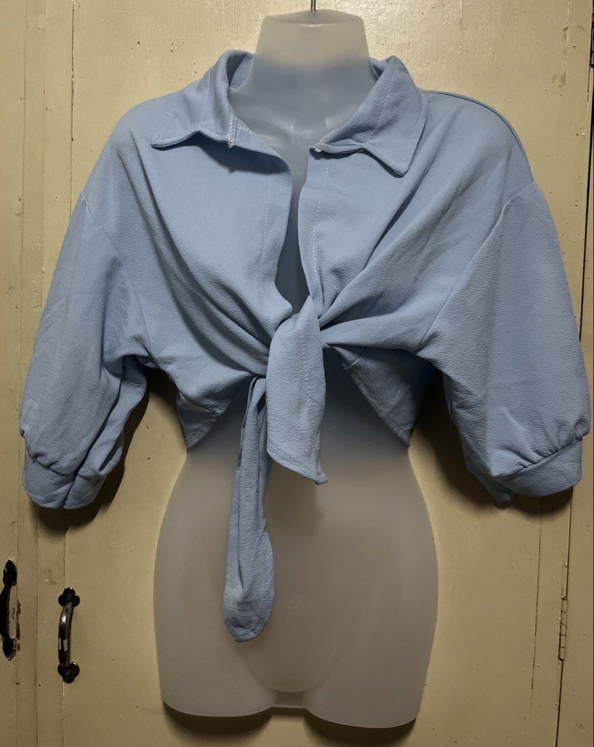 Light Blue Cropped Tie-Front Shirt Blouse (Category: Blouses) located in Tabuk. Submitted by zenwolf-1867 (Listing ID 1467973459, Image 1). Description: - Color: Light blue - Style: Collared crop top with half sleeves and front-tie knot - Fabric: Textured, lightweight, and breathable - Versatility: Pairs easily with high-waisted jeans, shorts, or skirts - Condition: Brand new / Excellent (ready to wear).