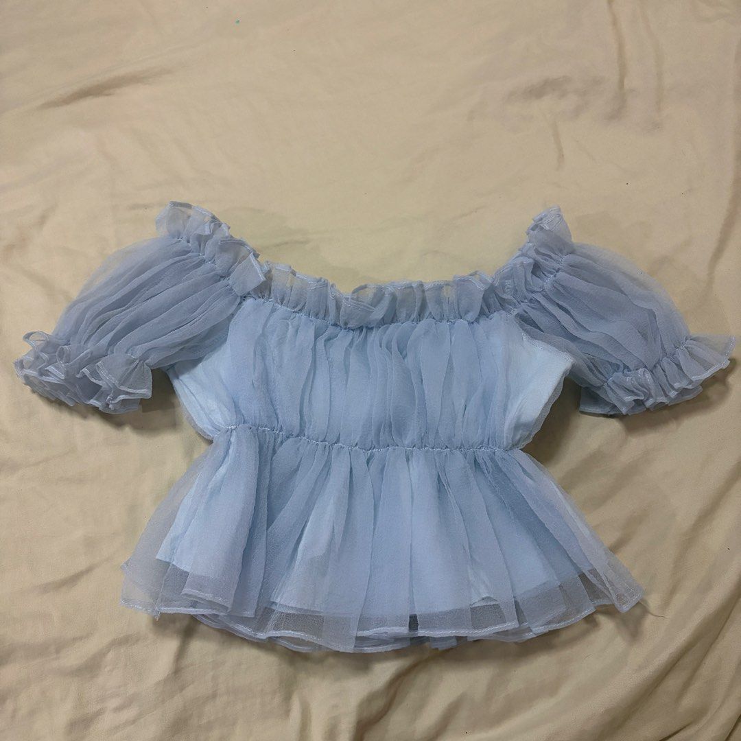 Light Blue Off Shoulder Ruffle Organza Top (Category: Blouses) located in Mandaluyong City. Submitted by afterceej (Listing ID 1467979817, Image 1). Description: - Color: Light blue - Material: Sheer organza fabric with gathered bodice texture - Design: Off-shoulder neckline, short ruffled sleeves, and a flared peplum hem with layered ruffles - Style: Dreamy, fairy-like aesthetic, perfect for dates or casual outings 📍 Mandaluyong 🚚 Shipping fee