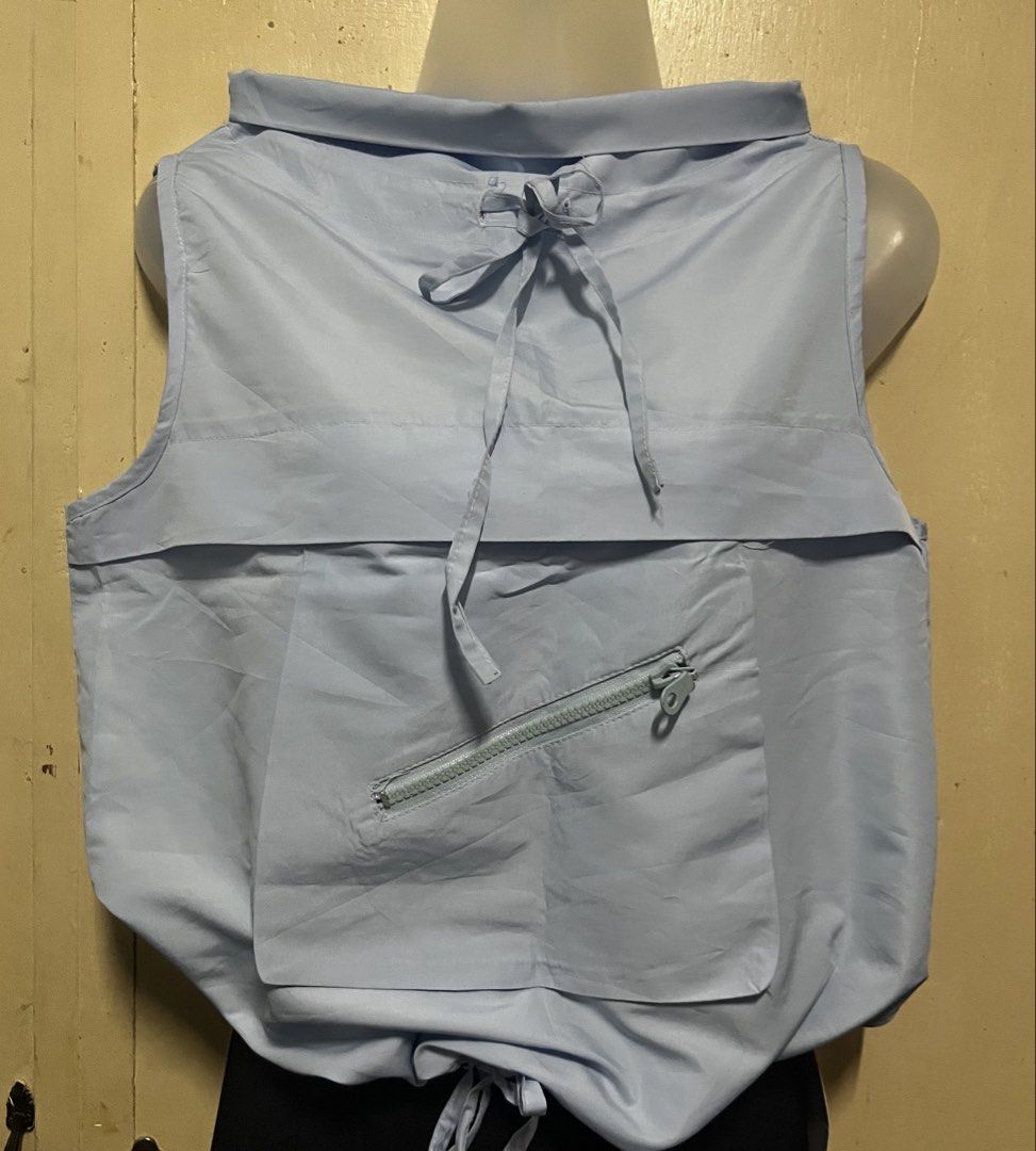 Light Blue Sleeveless Top with Front Zipper Pocket (Category: Sleeveless) located in Tabuk. Submitted by zenwolf-1867 (Listing ID 1467981146, Image 1). Description: - Style: Casual streetwear sleeveless top - Color: Light blue - Material: Smooth, nylon-like fabric - Neckline: Crew neck with front tie string detail - Pockets: Large front pocket with a stylish diagonal zipper - Hem: Adjustable drawstring for a gathered look - Condition: Great piece