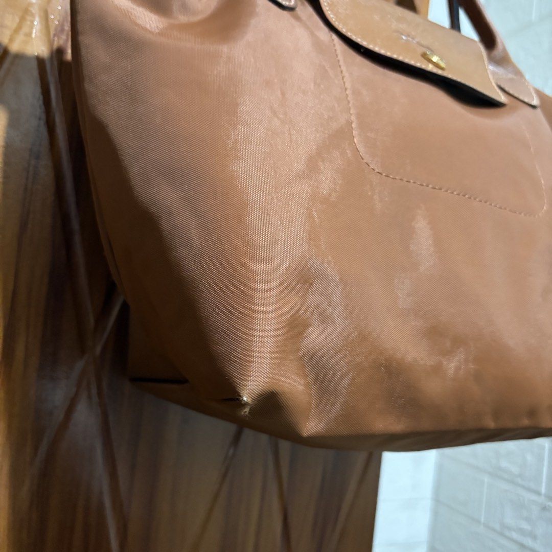 Longchamp Le Pliage Brown Tote Bag (Category: Tote Bags) located in Carmen. Submitted by rr_thrifts (Listing ID 1467931221, Image 3). Description: -Longchamp Le Pliage tote in a versatile brown shade - Durable nylon body with genuine leather handle and flap - Classic gold-tone hardware with secure zipper and snap button closure - Features standard short handles and a spacious, lightweight interior - Condition: Minor scuffing at one bottom corner 