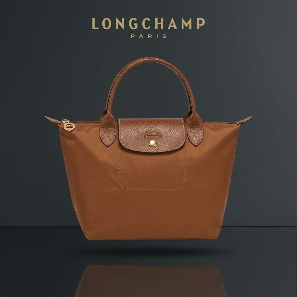 Longchamp Le Pliage Brown Tote Bag (Category: Tote Bags) located in Carmen. Submitted by rr_thrifts (Listing ID 1467931221, Image 1). Description: -Longchamp Le Pliage tote in a versatile brown shade - Durable nylon body with genuine leather handle and flap - Classic gold-tone hardware with secure zipper and snap button closure - Features standard short handles and a spacious, lightweight interior - Condition: Minor scuffing at one bottom corner 