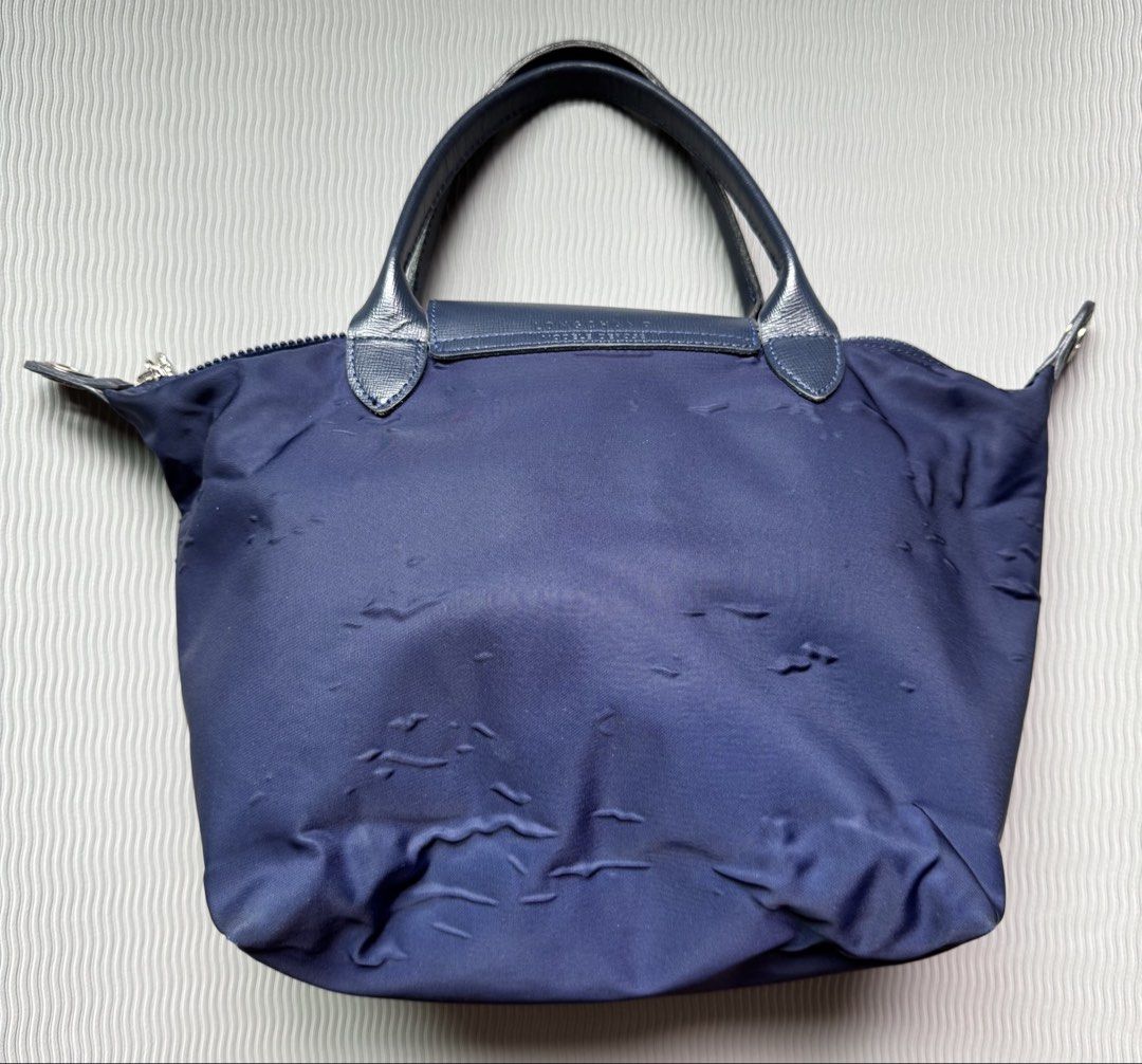 Longchamp Le Pliage Navy Blue Short Handle Handbag (Category: Luxury Bags & Wallets) located in Quezon City. Submitted by happibruce (Listing ID 1467851883, Image 2). Description: - Authentic Longchamp Le Pliage handbag in classic navy blue - Features dark leather trim, short top handles, and secure flap with snap closure - Spacious interior perfect for daily use, school, or work - Condition: Shows visible nylon wrinkling/fabric distortion and mi