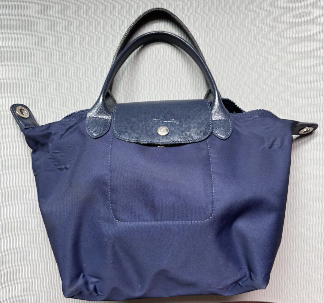 Longchamp Le Pliage Navy Blue Short Handle Handbag (Category: Luxury Bags & Wallets) located in Quezon City. Submitted by happibruce (Listing ID 1467851883, Image 1). Description: - Authentic Longchamp Le Pliage handbag in classic navy blue - Features dark leather trim, short top handles, and secure flap with snap closure - Spacious interior perfect for daily use, school, or work - Condition: Shows visible nylon wrinkling/fabric distortion and mi