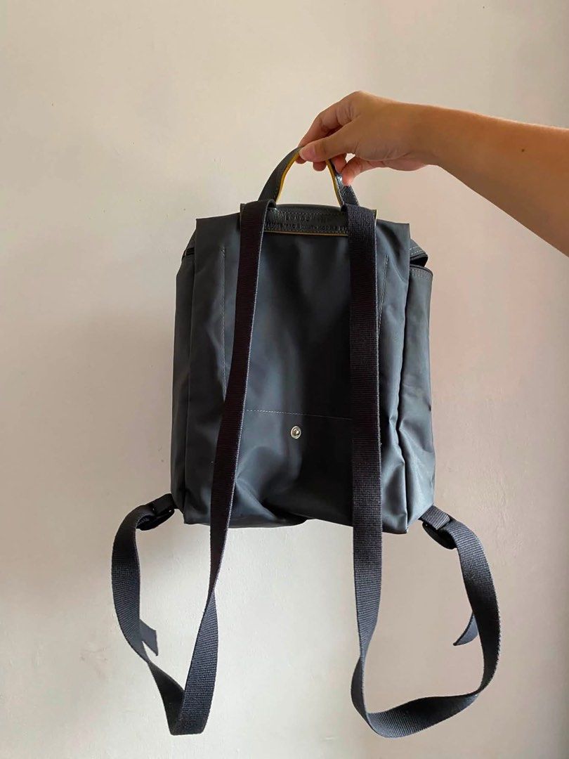 Longchamp Le Pliage Nylon Backpack Grey (Category: Backpacks) located in Iloilo. Submitted by clariceanyanicole (Listing ID 1467925439, Image 2). Description: - Material: Durable grey nylon with dark leather flap and gold snap button closure - Branding: Iconic gold horse logo embroidered on the front pocket - Hardware: Gold zipper pull with smooth zip opening - Comfort: Adjustable black fabric shoulder straps and top handle - Condition: Clean sti