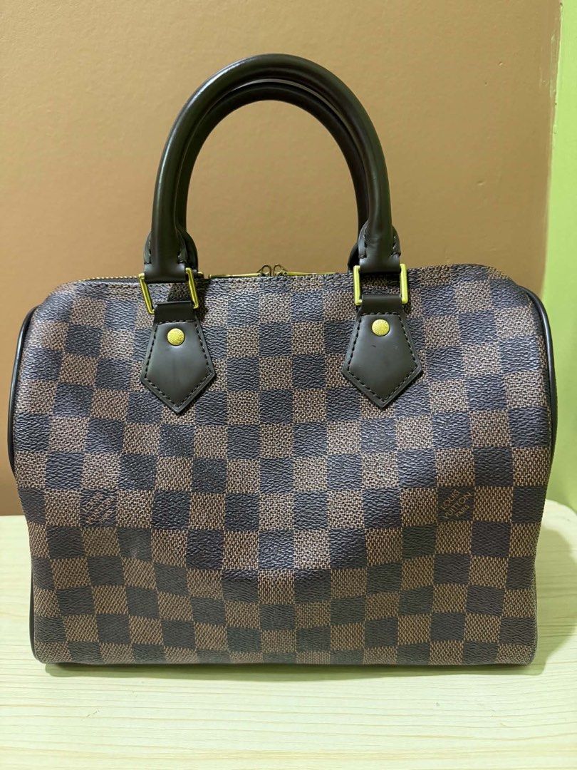 Louis Vuitton Damier Ebene Speedy 25 Handbag (Category: Luxury Bags & Wallets) located in Angono. Submitted by xxxallaboutbagsxxx (Listing ID 1467917366, Image 2). Description: Louis Vuitton Speedy 25 in Damier Ebene canvas. Iconic brown checked pattern with dark brown leather handles and gold-tone hardware. Red fabric interior lining with a slip pocket and D-ring. Includes padlock, two keys, and original dust bag. Date code FL1154 stamped inside