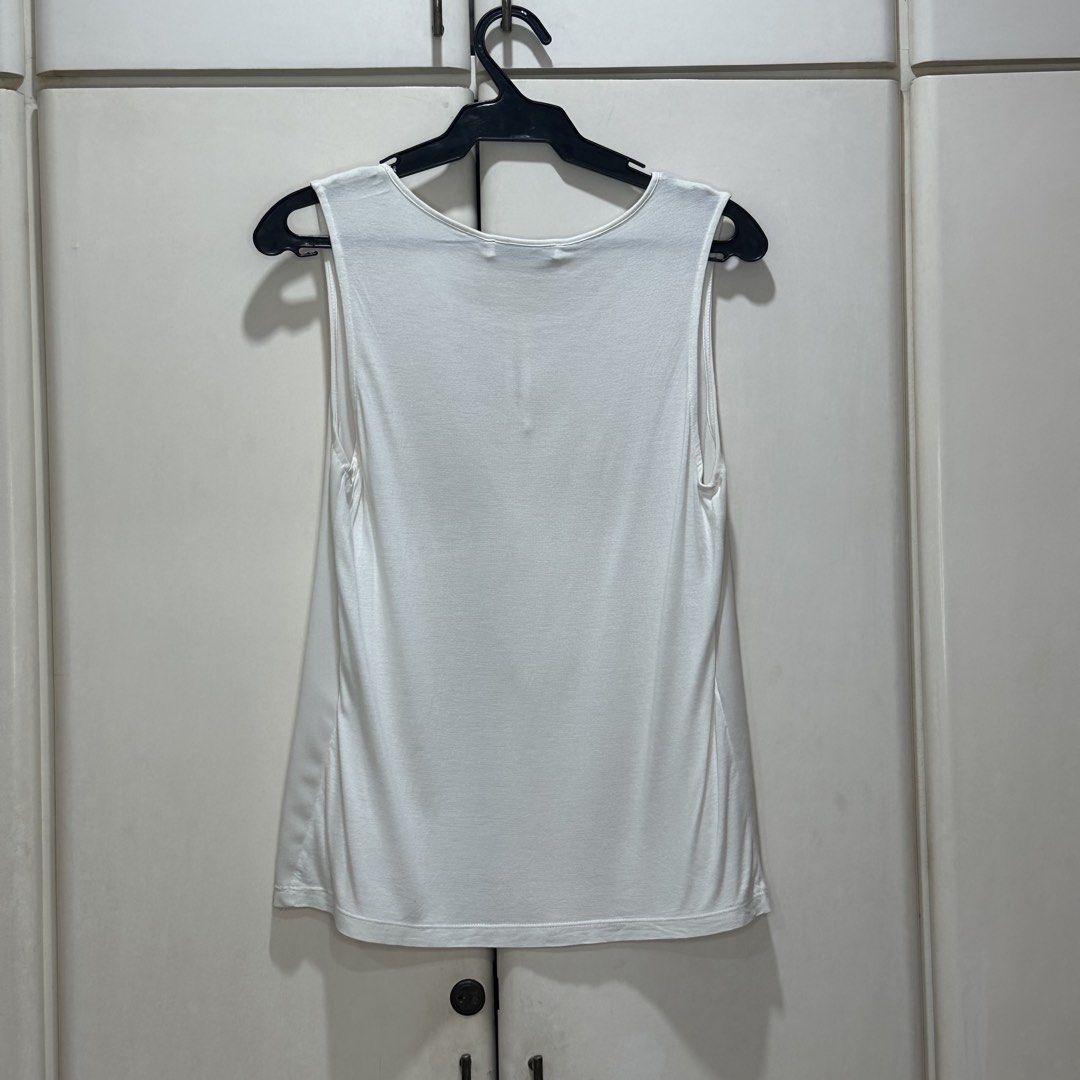 Mango - White Sleeveless Blouse (Category: Sleeveless) located in Muntinlupa City. Submitted by pickjes (Listing ID 1468022553, Image 2). Description: Brand: Mango Suit Size: Small Color: White Details: Semi-sheer, very versatile piece Measurements: • Width - 16.5” • Length - 24” Condition: Used max twice. No flaws. Wash tag detached. RFS: Decluttering White sleeveless tank top from Mango featuring a round scoop neckline and a subtle front keyhol