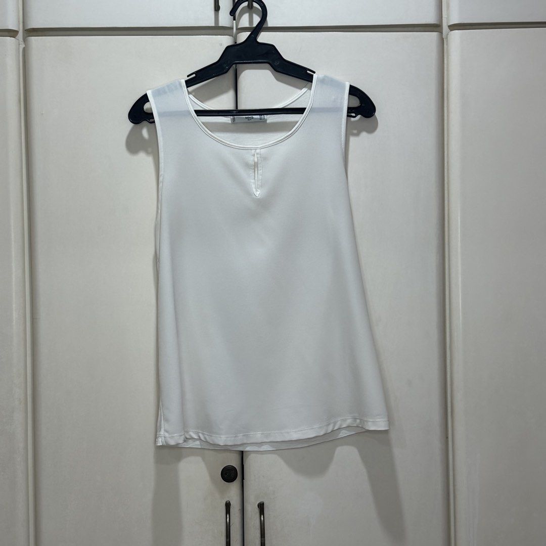 Mango - White Sleeveless Blouse (Category: Sleeveless) located in Muntinlupa City. Submitted by pickjes (Listing ID 1468022553, Image 1). Description: Brand: Mango Suit Size: Small Color: White Details: Semi-sheer, very versatile piece Measurements: • Width - 16.5” • Length - 24” Condition: Used max twice. No flaws. Wash tag detached. RFS: Decluttering White sleeveless tank top from Mango featuring a round scoop neckline and a subtle front keyhol