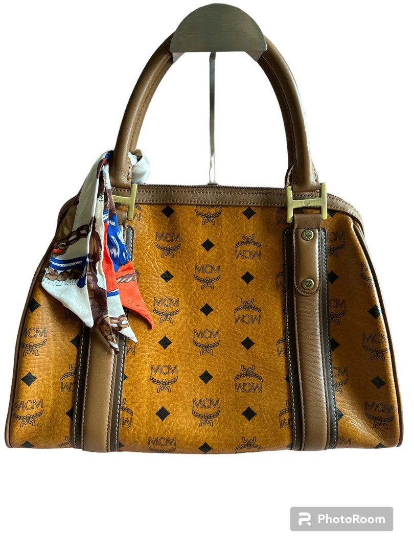 MCM Cognac Visetos Monogram Medium Shopper Tote Bag (Category: Luxury Bags & Wallets) located in Manila. Submitted by attypreciousyzncpa (Listing ID 1466150323, Image 2). Description: Classic MCM monogram print in rich cognac. Signature Visetos coated canvas with brown leather trim. Dual top handles, gold-tone hardware, and serial plate stamped H1188 on the front. Includes a detachable brass logo charm and a tied silk twill scarf on the side stra