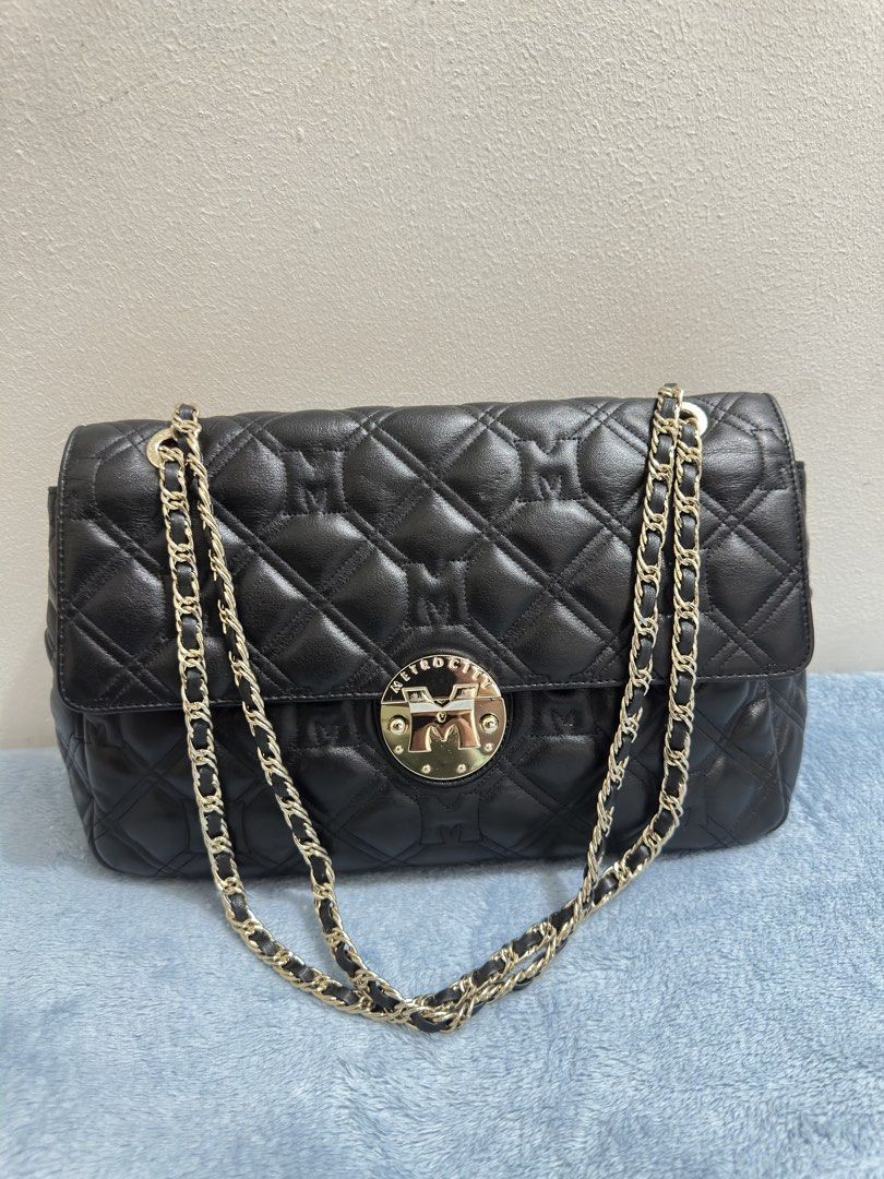 Metrocity Black Quilted Leather Chain Shoulder Bag (Category: Luxury Bags & Wallets) located in Calamba. Submitted by nympha0630 (Listing ID 1467860697, Image 1). Description: Metrocity black quilted leather shoulder bag. Gold chain strap and hardware. Turn-lock closure on the front flap. Structured rectangular shape with four protective metal feet on the bottom base. Quilted pattern includes embossed M monograms throughout the leather surface. C