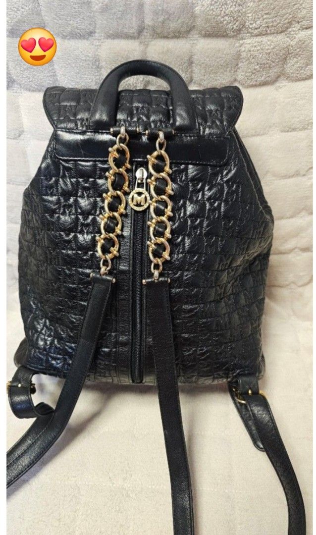 Metrocity Black Quilted Leather Backpack with Gold Hardware (Category: Backpacks) located in Quezon City. Submitted by jollythrift (Listing ID 1467988682, Image 2). Description: - Brand: Metrocity - Color: Classic Black - Material: Premium leather with all-over embossed logo pattern - Closure: Flap top with buckle and secure drawstring pull - Pockets: Front zipped pocket with trendy hanging leather tassels and chain detail, plus interior zipped s