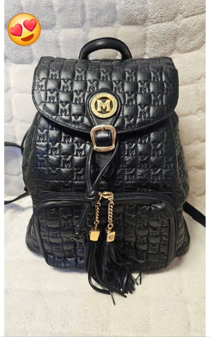 Metrocity Black Quilted Leather Backpack with Gold Hardware (Category: Backpacks) located in Quezon City. Submitted by jollythrift (Listing ID 1467988682, Image 1). Description: - Brand: Metrocity - Color: Classic Black - Material: Premium leather with all-over embossed logo pattern - Closure: Flap top with buckle and secure drawstring pull - Pockets: Front zipped pocket with trendy hanging leather tassels and chain detail, plus interior zipped s