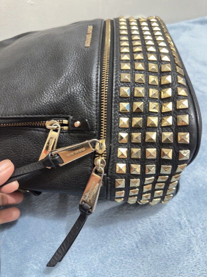 Michael Kors Black Leather Studded Backpack (Category: Backpacks) located in Calamba. Submitted by nympha0630 (Listing ID 1467874137, Image 3). Description: - Brand: Michael Kors - Material: Premium black pebbled leather - Hardware: Gold-tone with engraved zipper pulls & trendy pyramid studs on the front - Compartments: Secure zip-around closure and front zippered pocket - Straps: Adjustable black leather shoulder straps + top handle - Condition: