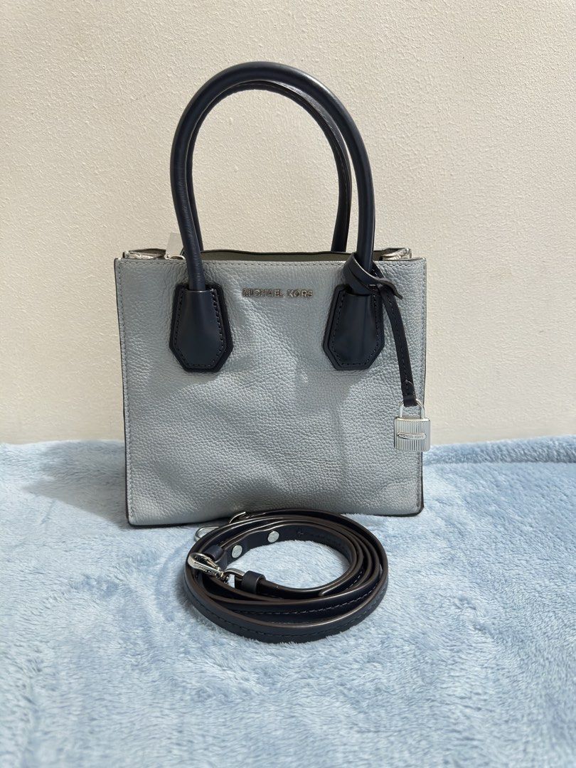 Michael Kors Mercer Mini Light Blue Navy (Category: Tote Bags) located in Calamba. Submitted by nympha0630 (Listing ID 1467853955, Image 1). Description: - Brand: Michael Kors - Style: Mini Tote Bag - Color: Light blue with navy blue handles - Material: Premium pebbled leather - Hardware: Silver-tone with front padlock charm - Strap: Includes detachable crossbody strap - Base: Protective bottom feet - Handles: Dual top carry handles - Interior: C