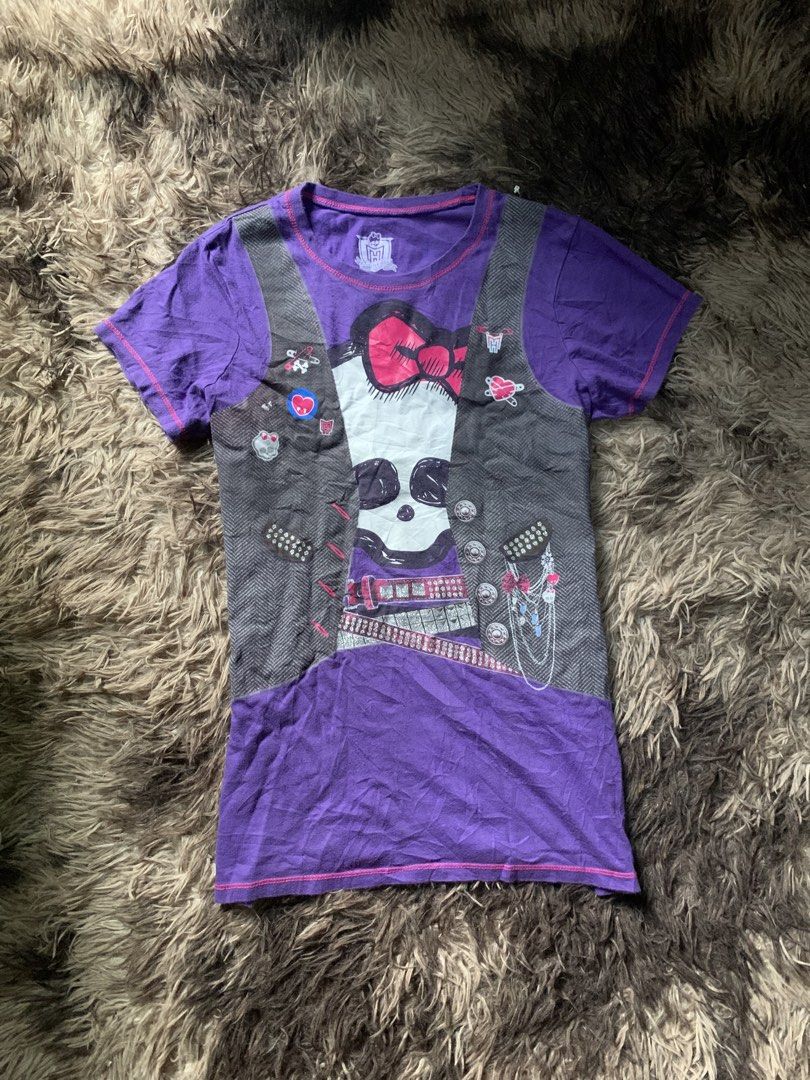 Monster High Graphic Tee Purple (Category: Shirts) located in Cebu City. Submitted by selamethrift (Listing ID 1467949940, Image 1). Description: - Brand: Monster High (2013 Mattel) - Size: XL but fits s-m - Color: Purple - Material: 100% Cotton (Made in El Salvador) - Design: Trompe l'oeil vest print with skull graphic, pink bow, and studded belt details - Style: Short sleeves, crew neck - Condition: Excellent, comfortable daily wear - Perfect f