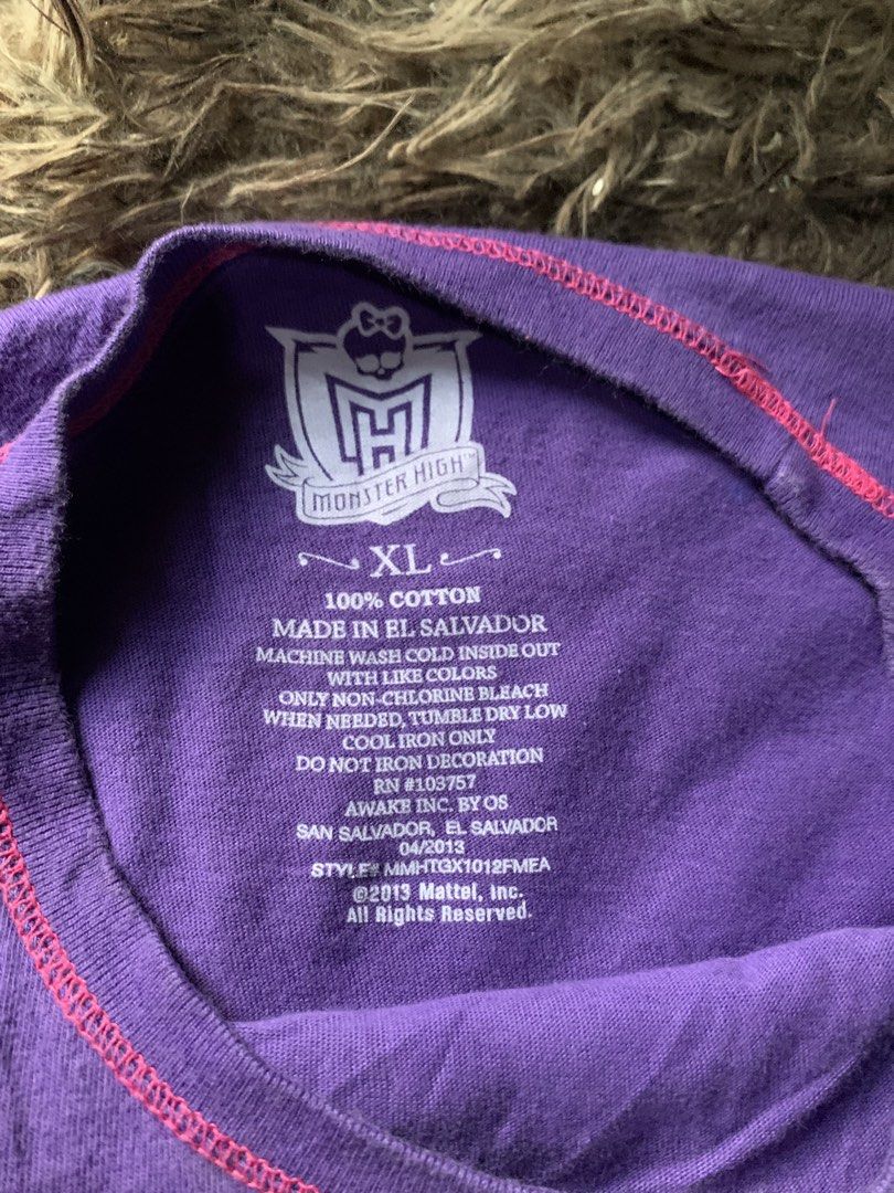 Monster High Graphic Tee Purple (Category: Shirts) located in Cebu City. Submitted by selamethrift (Listing ID 1467949940, Image 3). Description: - Brand: Monster High (2013 Mattel) - Size: XL but fits s-m - Color: Purple - Material: 100% Cotton (Made in El Salvador) - Design: Trompe l'oeil vest print with skull graphic, pink bow, and studded belt details - Style: Short sleeves, crew neck - Condition: Excellent, comfortable daily wear - Perfect f