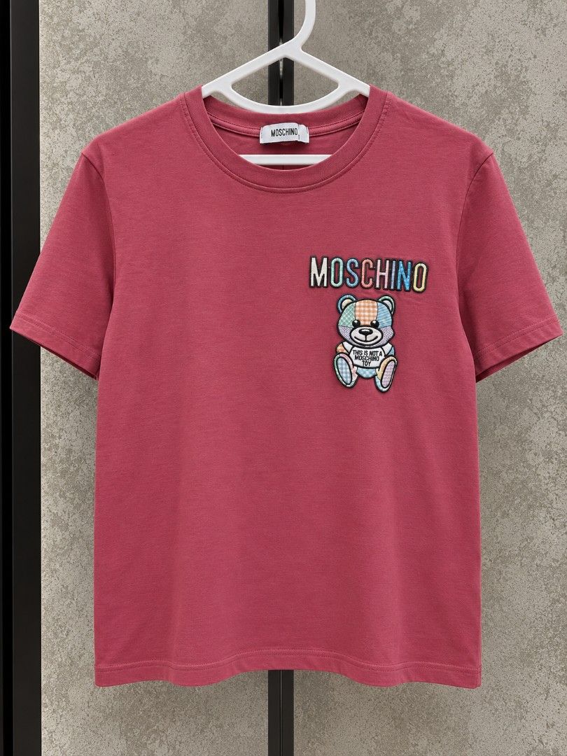 Moschino T-Shirt (Category: Shirts) located in Taguig. Submitted by roniquefinds (Listing ID 1467861338, Image 1). Description: - Brand: Moschino - Size/Fit: Regular fit, crew neck, short sleeve - Details: Multi-color embroidered teddy bear patch with 'Moschino' and 'This is not a Moschino toy' text - Material: Clean, premium cotton - Condition: Excellent, ready to wear.