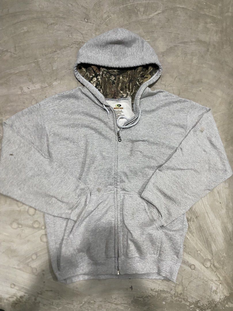 Mossy Oak Camo Lined Grey Zip Realtree (Category: Coats, Jackets and Outerwear) located in Las Pinas. Submitted by 2fly.margiela (Listing ID 1467870546, Image 3). Description: - Brand: Mossy Oak - Size: Medium - Color: Grey with camo-lined hood - Material: Cotton blend - Features: Full zip-up closure, drawstring hood, and front kangaroo pockets - Fit: Standard fit, perfect for casual wear and cooler days - Condition: Excellent.