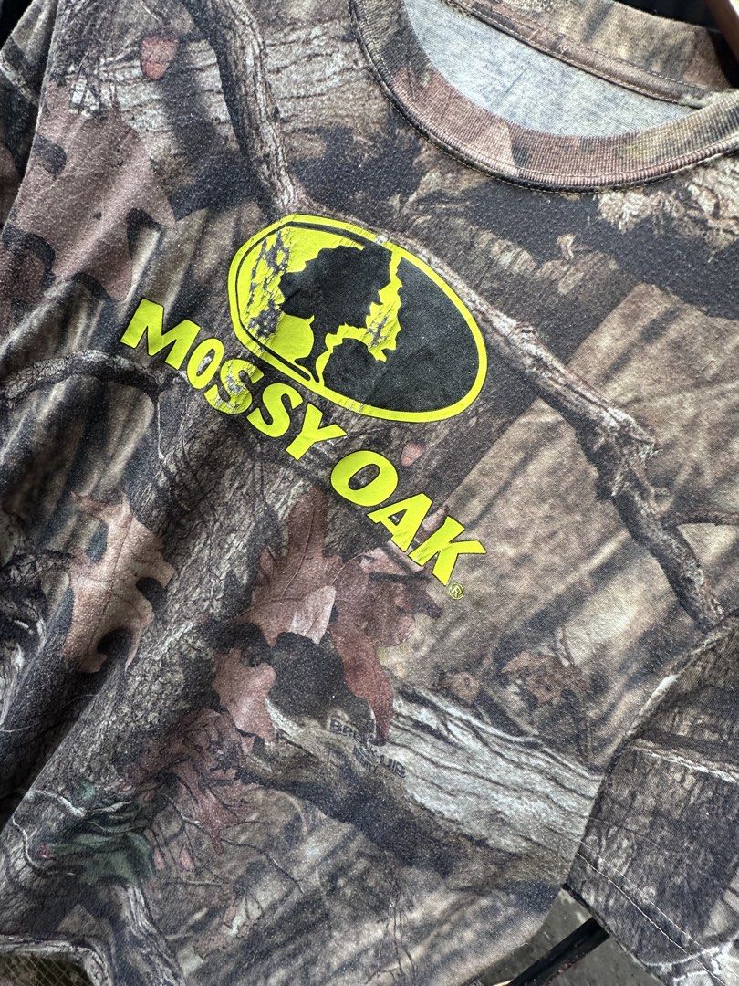 Mossy Oak Camo T-Shirt Break-Up Pattern (Category: Tshirts & Polo Shirts ) located in Lapu Lapu. Submitted by gabocamaon03138 (Listing ID 1468024700, Image 2). Description: - Brand: Mossy Oak - Design: Classic tree branch and leaf camo print - Detail: Bright yellow chest logo with vintage cracking - Style: Short sleeves, crew neck - Material: Soft, broken-in cotton blend - Condition: Great pre-loved condition, super comfortable - Perfect for outd