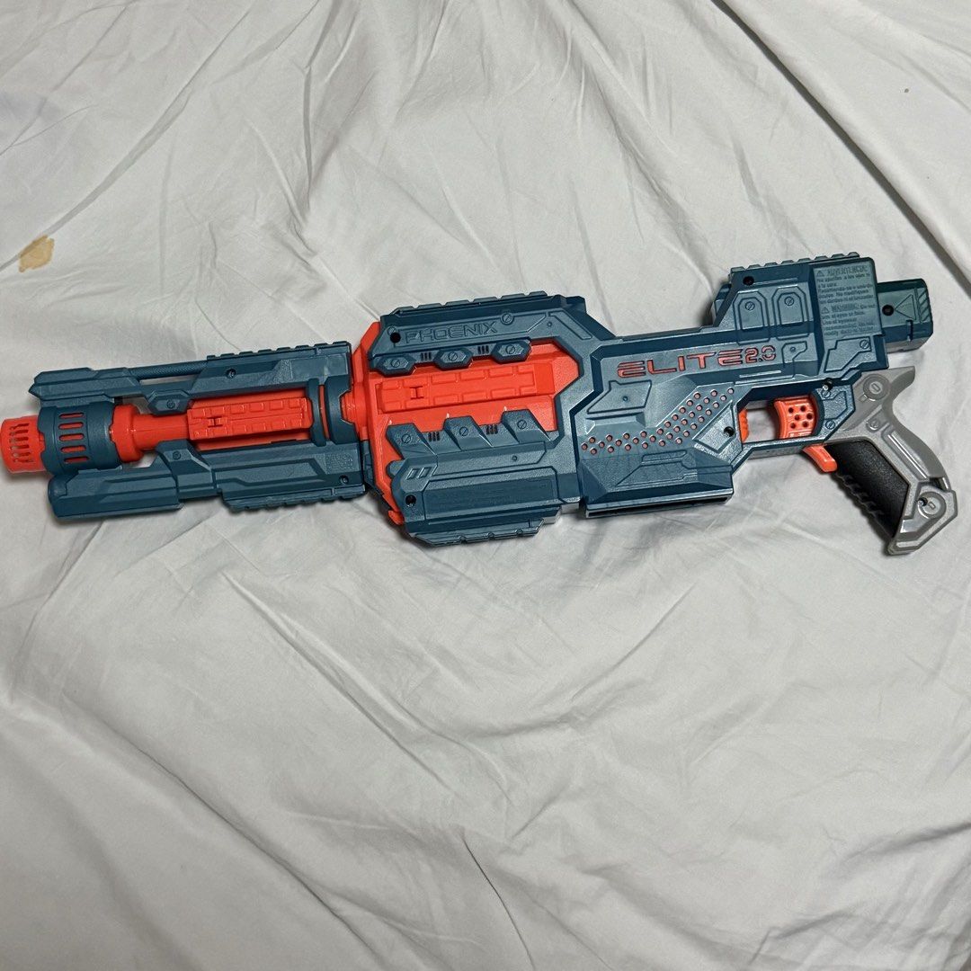 Nerf Elite 2.0 Phoenix CS-10 Blaster (Category: Action & Battle Toys) located in Marikina City. Submitted by lovegoeson (Listing ID 1467860000, Image 2). Description: - Model: Nerf Elite 2.0 Phoenix CS-6 motorized blaster - Color: Classic blue and orange scheme - Features: Top and bottom tactical rails, attached barrel extension - Grip: Textured grey grip for better handling - Power: Battery-operated for rapid firing - Condition: Clean exterior, 