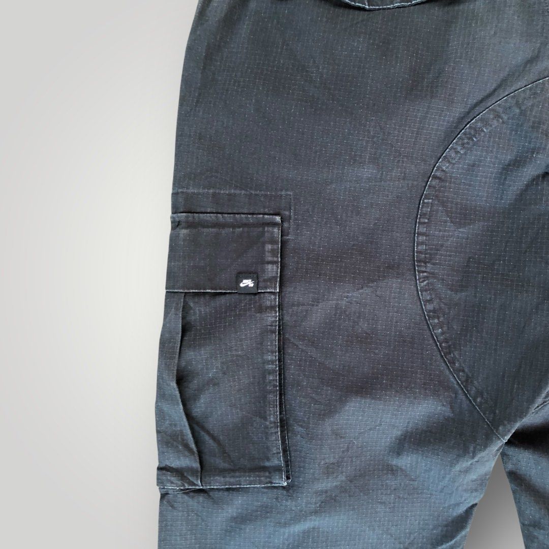 NIKE SB KEARNY CARGO PANTS (Category: Joggers) located in Paranaque City. Submitted by lesstash001 (Listing ID 1467978227, Image 3). Description: - Brand: Nike SB - Color: Classic Black - Material: Durable ripstop fabric texture - Pockets: Multiple utility pockets on sides and back - Fit: Adjustable drawstring cuffs at the bottom hem - Details: D-ring near front waistband and Nike SB branding tag - Closure: Button closure with zipper fly NIKE SB 