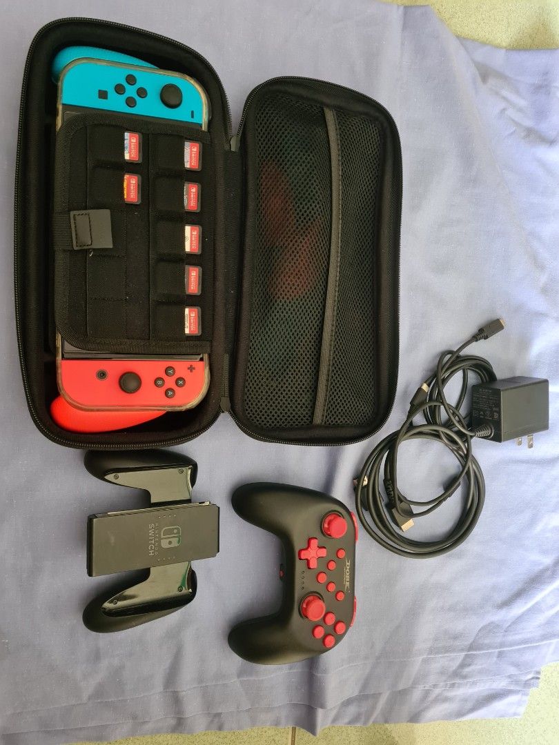Nintendo Switch Console with Games, Controller and Case (Category: Nintendo) located in Malasiqui. Submitted by _clickmycloset (Listing ID 1468042431, Image 1). Description: Nintendo Switch oled in neon blue and red joy-cons. Includes a Dobe wireless controller, black carrying case, charging power adapter, HDMI cable, and extra grip attachments. Six physical game cartridges included: Jump Force Deluxe Edition, Resident Evil Revelations, FIFA 22 L