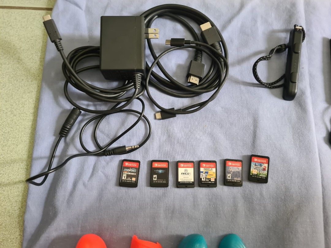 Nintendo Switch Console with Games, Controller and Case (Category: Nintendo) located in Malasiqui. Submitted by _clickmycloset (Listing ID 1468042431, Image 3). Description: Nintendo Switch oled in neon blue and red joy-cons. Includes a Dobe wireless controller, black carrying case, charging power adapter, HDMI cable, and extra grip attachments. Six physical game cartridges included: Jump Force Deluxe Edition, Resident Evil Revelations, FIFA 22 L